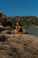 Femme brune au milieu de rocher et de la mer portant la maillot de bain une pièce Ama kaki