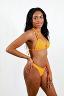 Femme de profil portant le haut de maillot de bain Sasha orange et le bas de maillot de bain Hena en orange